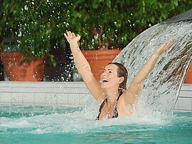 Frau genießt Wellness unter einem Wasserstrahl